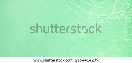 Abstract summer banner background Transparent green clear water surface texture with ripples and splashes. Water wave in sunlight, copy space, top view Cosmetics moisturizer micellar toner emulsion