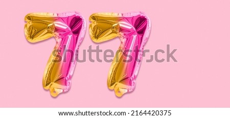 Rainbow foil balloon number, digit seventy seven on a pink background. Birthday greeting card with inscription 77. Top view. Numerical digit. Celebration event, template. Banner.