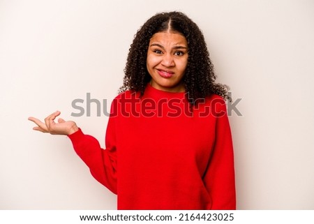 Young African American woman isolated on white background doubting and shrugging shoulders in questioning gesture. Royalty-Free Stock Photo #2164423025