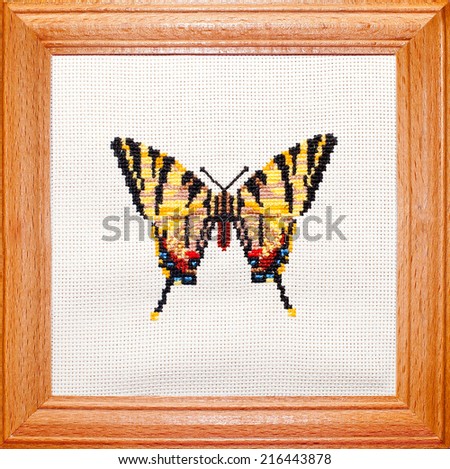 Cross stitch embroidery butterfly on canvas in wooden frame 
