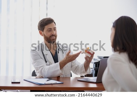 Professional doctor consults patient and demonstrate the model of several spines in modern clinic