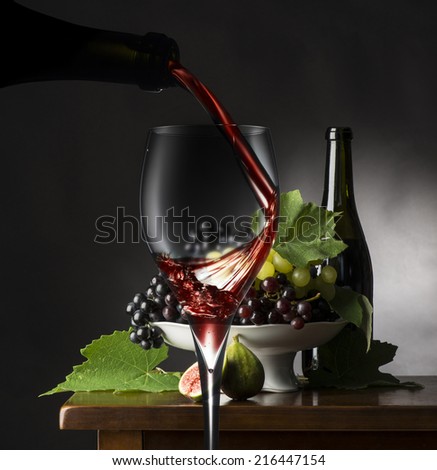 Red wineGlass of red wine on the wooden table with grapes