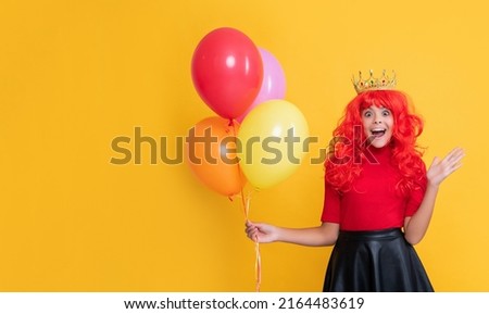 happy child in crown with helium balloon on yellow background. wow