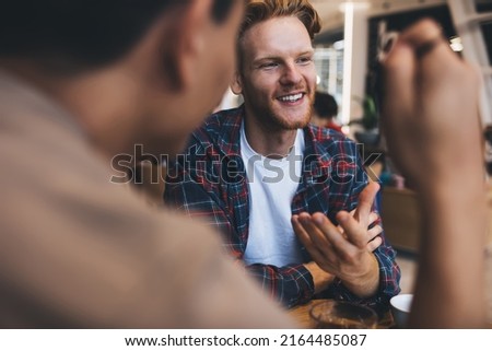 Businessmen talking during working at wooden table in office space. Concept of business cooperation and teamwork. Idea of modern successful men. Smiling bearded caucasian guy gesticulating with hand Royalty-Free Stock Photo #2164485087
