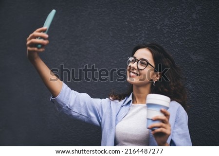 Millennial female influencer posing for camera while making selfie on mobile phone app. Social network photo, young woman photographing herself on smartphone while blogging. Online Video calling
