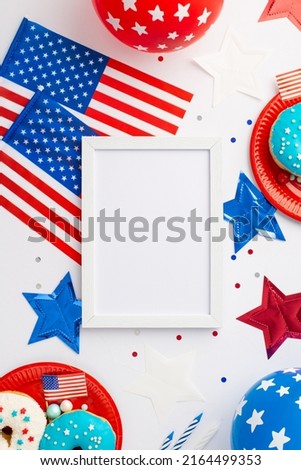 USA Independence Day concept. Top view vertical photo of photo frame national flags balloons stars plates with donuts and confetti on isolated white background with blank space