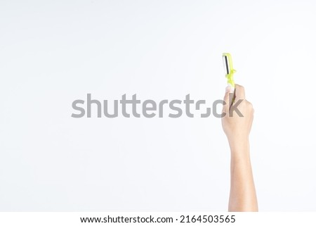 Hand holding plastic fruit peeler with green handle on white background