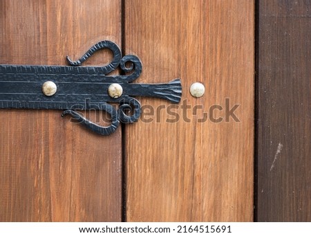 Wooden craft textured surface of the enter door with black and silver metallic element as a comfortable background with different grungy structures. 