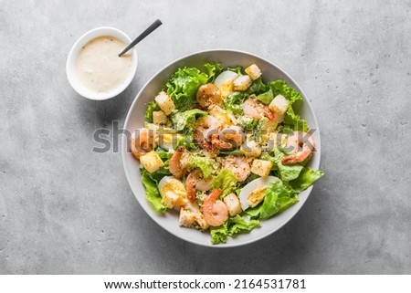 Shrimp Salad. Seafood Caesar Salad with prawns, parmesan cheese and caesar dressing on gray stone background, top view, copy space. Royalty-Free Stock Photo #2164531781