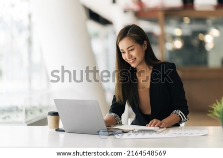 Cheerful business lady working on laptop in office, Asian happy beautiful businesswoman in formal suit work in workplace. Attractive female employee office worker smile. Royalty-Free Stock Photo #2164548569