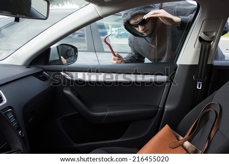 Thief is looking for unattended valuables left in a car Royalty-Free Stock Photo #216455020
