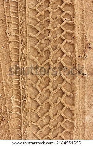 Tire prints on a wet yellow sandy road. Top view. Background for the design. Vertical photo. Royalty-Free Stock Photo #2164551555