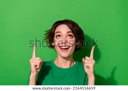 Photo of excited dreamy woman wear casual t-shirt pointing looking up empty space isolated green color background