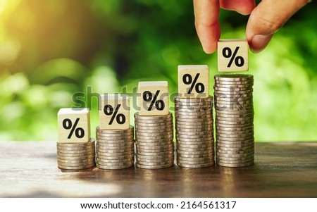 Hand picked percentage sign on wooden cubes which lay down on increasing coins stacking for interest rate and business profit growth concept. Finance and Mortgage Interest Rate Ideas.
