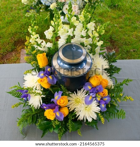 Cremation urn at funeral ceramony with floral arrangement Royalty-Free Stock Photo #2164565375