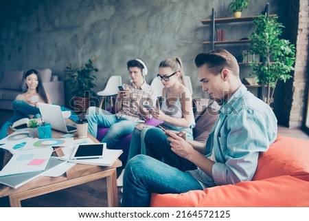 Portrait of group people sitting beanbag use telephone chatting typing office room indoors Royalty-Free Stock Photo #2164572125