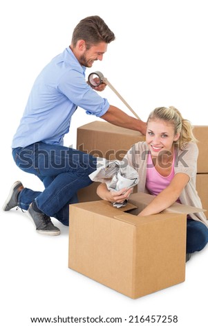 Young couple packing moving boxes against white background