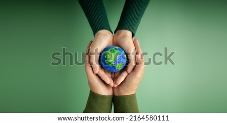 World Earth Day Concept. Green Energy, ESG, Renewable and Sustainable Resources. Environmental Care. Hands of People  Embracing a Handmade Globe. Protecting Planet Together. Top View Royalty-Free Stock Photo #2164580111