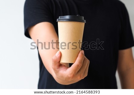 Young man hand holding coffee paper cup on white background. Mockup for you designs.