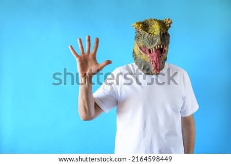 Funny laughing dinosaur head on human body on white t-shirt on blue background, showing five fingers with the hand, Clip art, negative space.