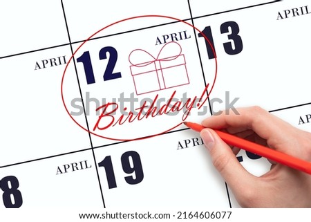 12th day of April.  The hand circles the date on the calendar 12 April, draws a gift box and writes the text Birthday. Holiday. Spring month, day of the year concept.