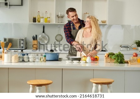 Joyful couple enjoying romantic date in kitchen, they are flirting and cooking dinner Royalty-Free Stock Photo #2164618731
