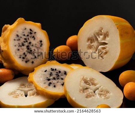 Golden Dragon fruit, Korean melon and kumquats displayed on a black background. 