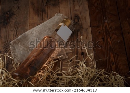 250 ml bottle of pink wine with blank label lying on wooden shavings, wooden table. Alcohol drink.