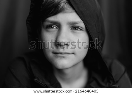 Black and white portrait of teenage boy on dark background. Low key close up shot of a young teen boy. Black and white photography. Selective focus. Joy, happiness