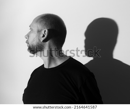 Portrait of a man and his shadow against white wall background. Salvador, Bahia, Brazil