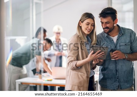 Two young businesspeople using a digital tablet while standing in a boardroom. Two business colleagues having a discussion during a meeting. Royalty-Free Stock Photo #2164655469