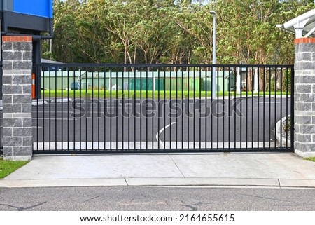 Automatic steel sliding entrance gate across a drive way Royalty-Free Stock Photo #2164655615