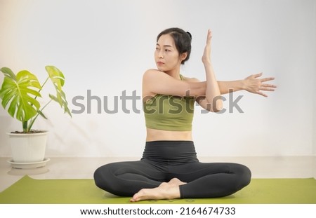 Woman do yoga on the green yoga mat to meditate and exercise in the home.