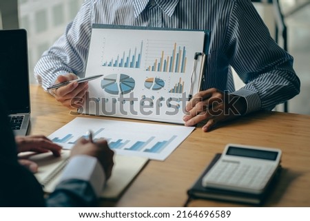 business people meet with design ideas business planning Picture of two young businessmen holding pens and graph papers at a meeting discussing charts and graphs showing successful teamwork.