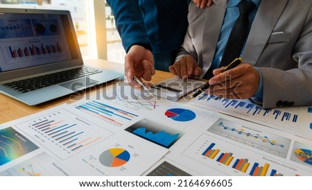 business people meet with design ideas business planning Picture of two young businessmen holding pens and graph papers at a meeting discussing charts and graphs showing successful teamwork.