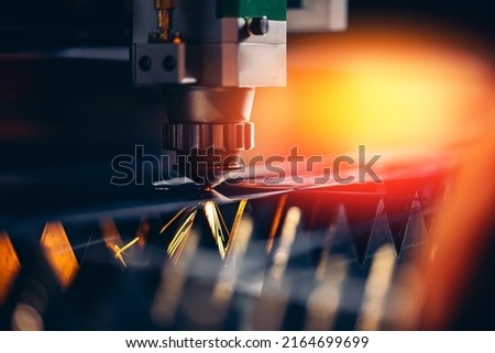 Industrial Macro CNC laser machine cutting sheet metal with light spark. Royalty-Free Stock Photo #2164699699