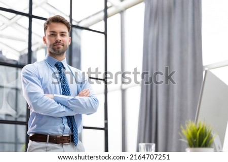 Portrait of happy businessman with arms crossed standing in office Royalty-Free Stock Photo #2164707251