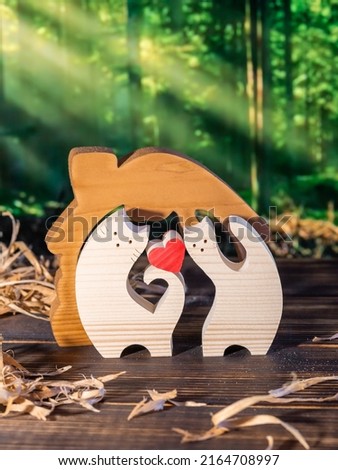 Wooden puzzle in the form of a handmade cat family on the background of the forest.
