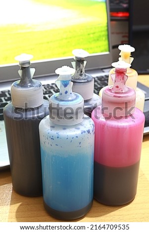 several bottles of printer ink on the table with various colors, namely black, yellow, blue and magenta Royalty-Free Stock Photo #2164709535