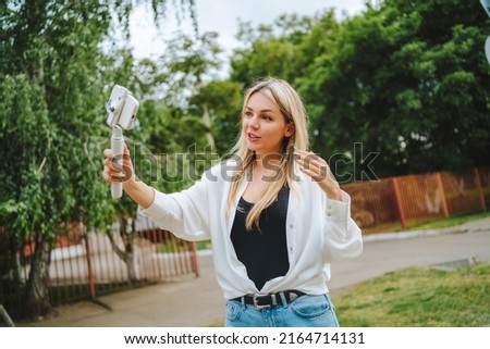Beautiful young blonde woman writes down a vlog and takes a selfie. High quality photo