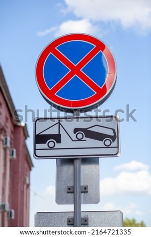The road sign prohibits stopping against the background of buildings and cars. Close-up road signs No stopping and Tow Away Zone in city. Road signs of Stopping is prohibited 