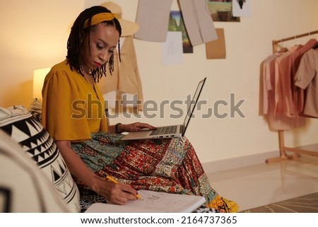 Fashion designer discussing details of order with client via e-mail and drawing sketch