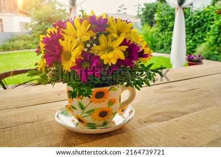 Composition of flowers in a tea mug on a wooden table in the morning in summer or spring. Postcard good morning, Happy Mother's Day, March 8th.