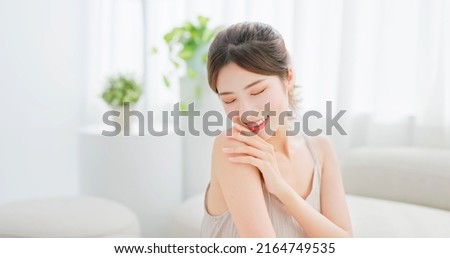 beauty skin care asian woman with brunette ponytail touches her shoulder eye closed