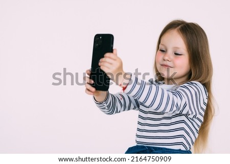 Portrait of an excited little girl taking a selfie isolated over white background