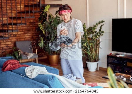 Asian guy making photo on the phone and holding a new clothes