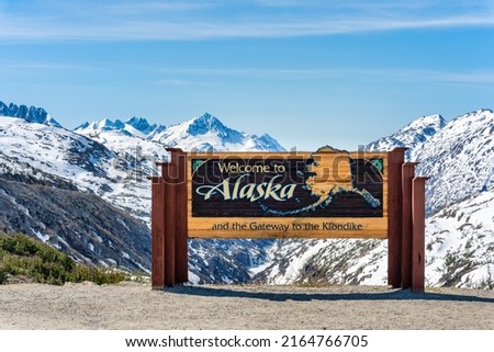 Alaska welcome sign with snow-capped mountains in the background Royalty-Free Stock Photo #2164766705