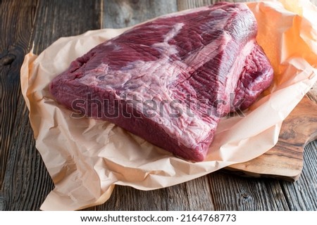 Raw beef brisket with butcher paper isolated on wooden table 