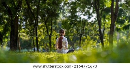 Woman relaxingly practicing meditation yoga in the forest to attain happiness from inner peace wisdom with beam of sun light for healthy mind and soul Royalty-Free Stock Photo #2164771673
