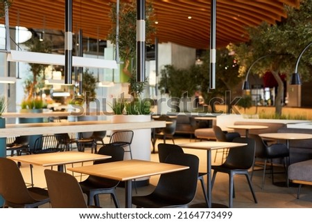 Background image of empty food court interior with wooden tables and warm cozy light setting, copy space Royalty-Free Stock Photo #2164773499